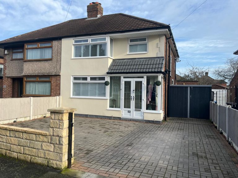 Semi-detached house rendered in cream with new white fascias and soffits, black guttering and a tiled porch canopy over the front door, block-paved driveway