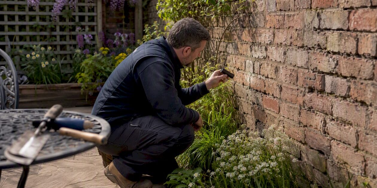 Homeowner inspecting cracks in brick wall
