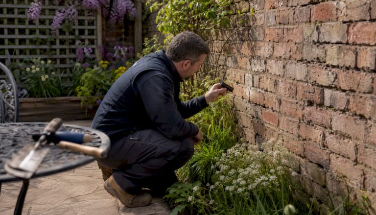 Homeowner inspecting cracks in brick wall