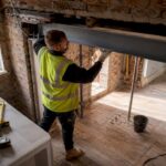 Builder installing steel RSJ beam indoors