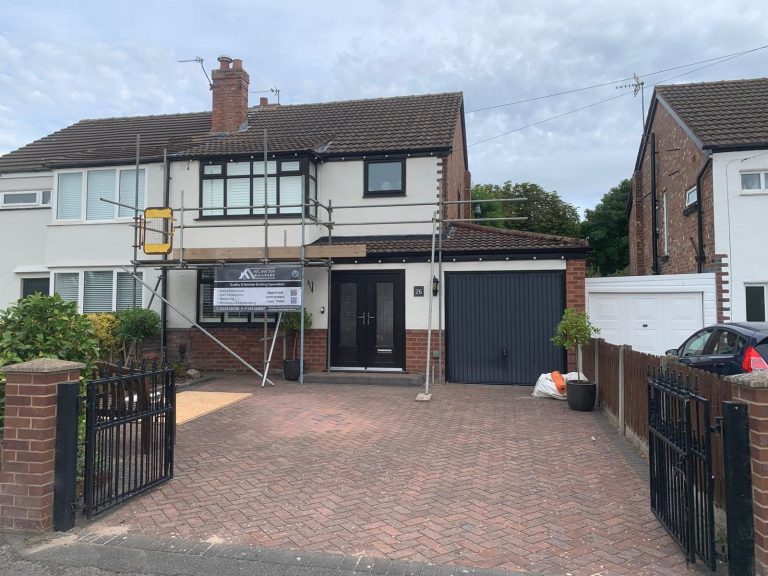 Semi-detached house freshly rendered in white with black windows and door, AJC and Son Builders board on the scaffolding, block-paved driveway in front