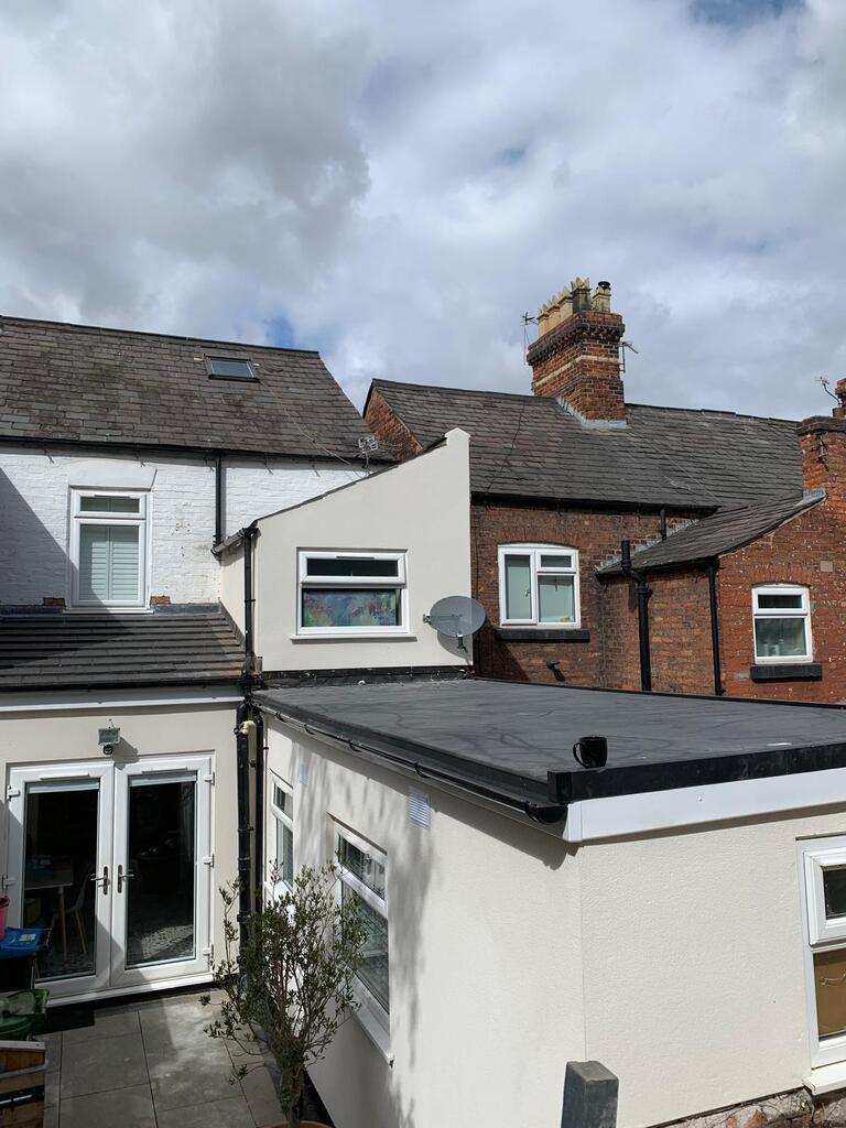 Rear of the house with the single-storey extension and upper wall rendered in cream, new black guttering and a flat roof